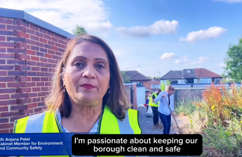 Cllr Anjana Patel in a high viz jacket in Rayners Lane. In the background is a wall and some houses. 
