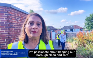 Cllr Anjana Patel in a high viz jacket in Rayners Lane. In the background is a wall and some houses. 
